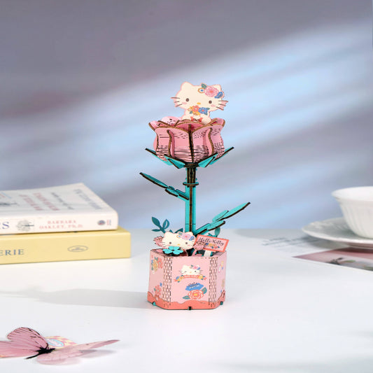 Decorative pen holder with a pink rose design on a table with books and a cup in the background.
