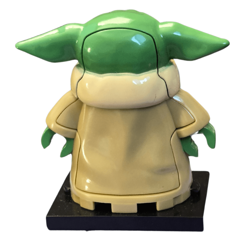 Toy figure of a character with green ears and beige body on a white background