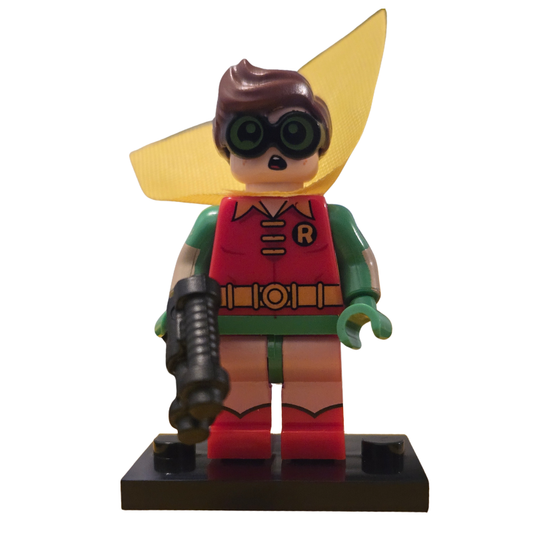 Toy figure of a character in a red and green costume with a yellow cape on a white background