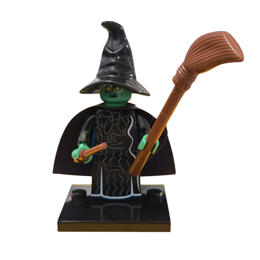 Toy figure of a witch with a broom on a white background