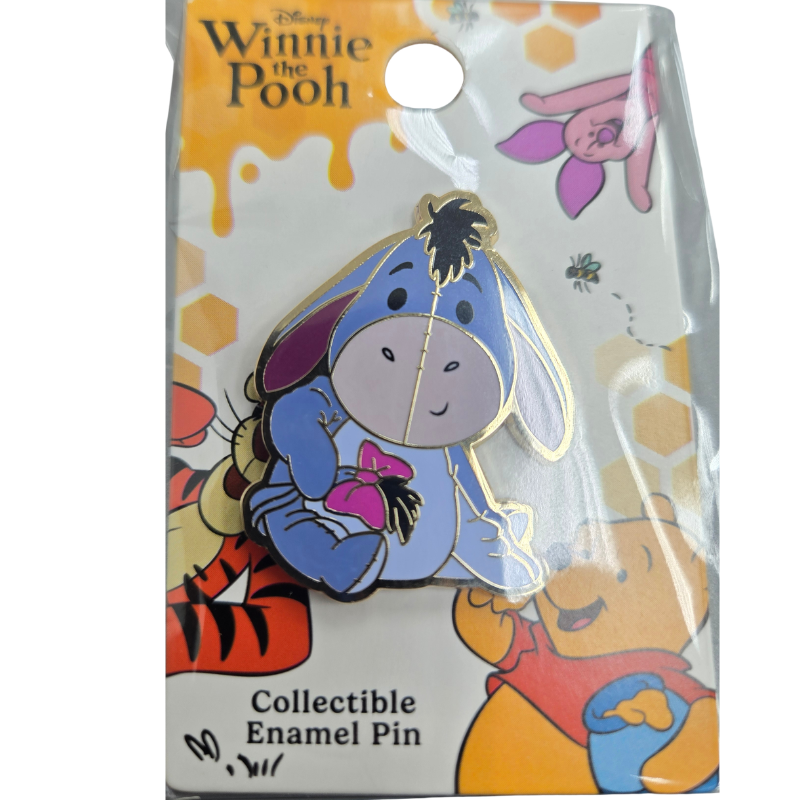 Disney Winnie the Pooh collectible enamel pin of Eeyore holding a pink bow, mounted on its original illustrated blister card.
