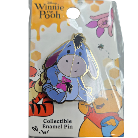 Disney Winnie the Pooh collectible enamel pin of Eeyore holding a pink bow, mounted on its original illustrated blister card.