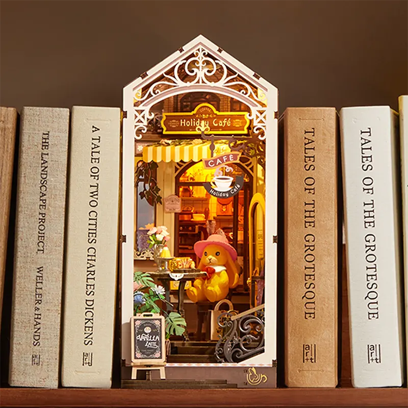 Miniature cafe scene inside a bookshelf with books titled 'A Tale of Two Cities' and 'Tales of the Grotesque'.