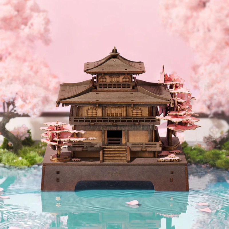 Model of a traditional Japanese temple with cherry blossom trees in the background