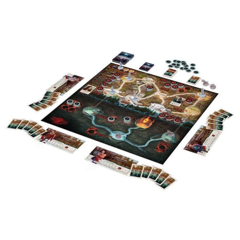 A board game set displayed on a clean white background, featuring a large illustrated game board with fantasy terrain, multiple character cards, play cards, tokens, dice, and other game components arranged around it.