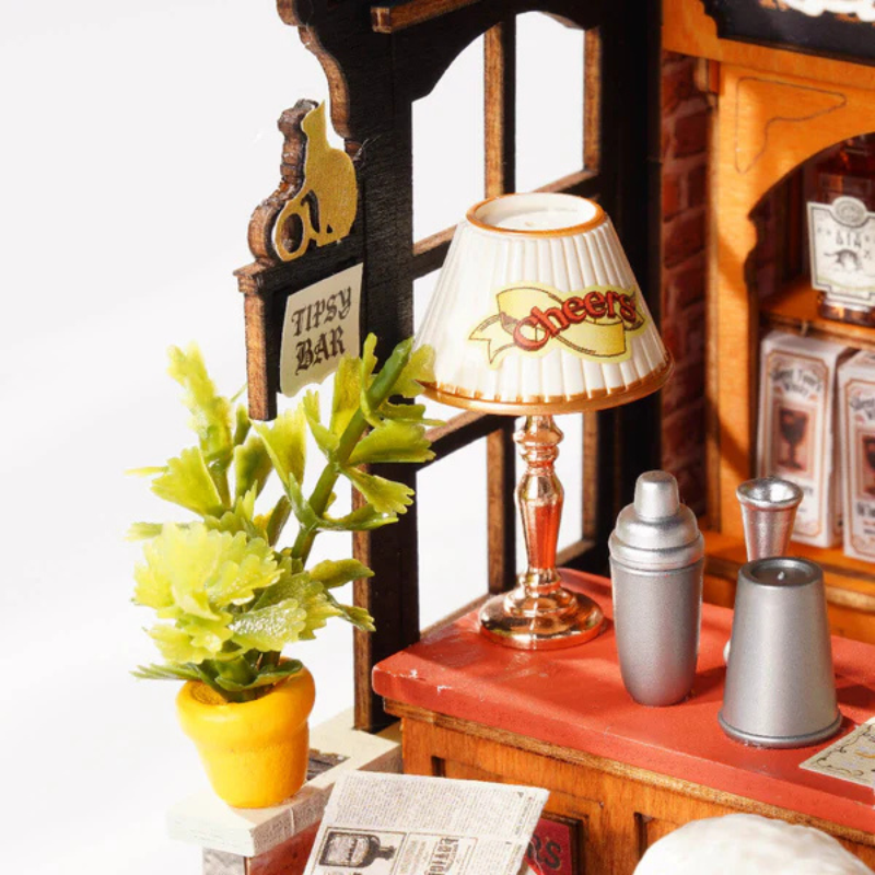 Miniature bar setup with lamp, shakers, and plant on a white background