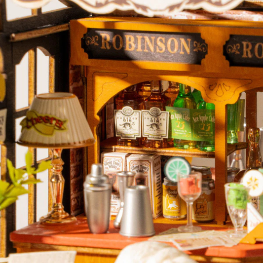 Miniature bar setup with 'Robinson' sign and various bottles on a wooden shelf.